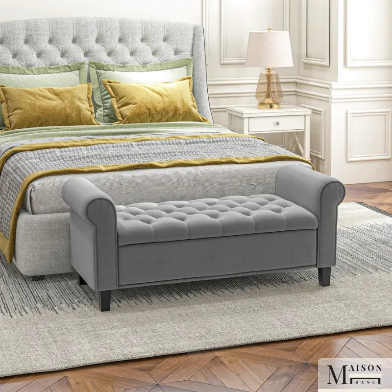 Banc coffre classique en velours gris capitonné, style suite Bellina, avec repose-pieds et détails élégants.